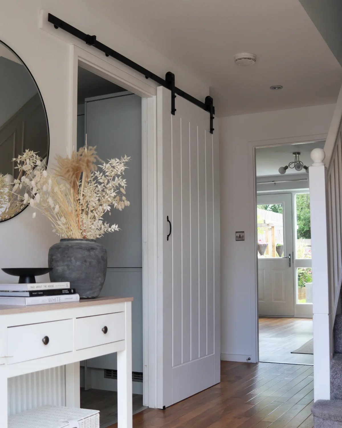 White sliding barn door on black hardware in a bright home interior hallway