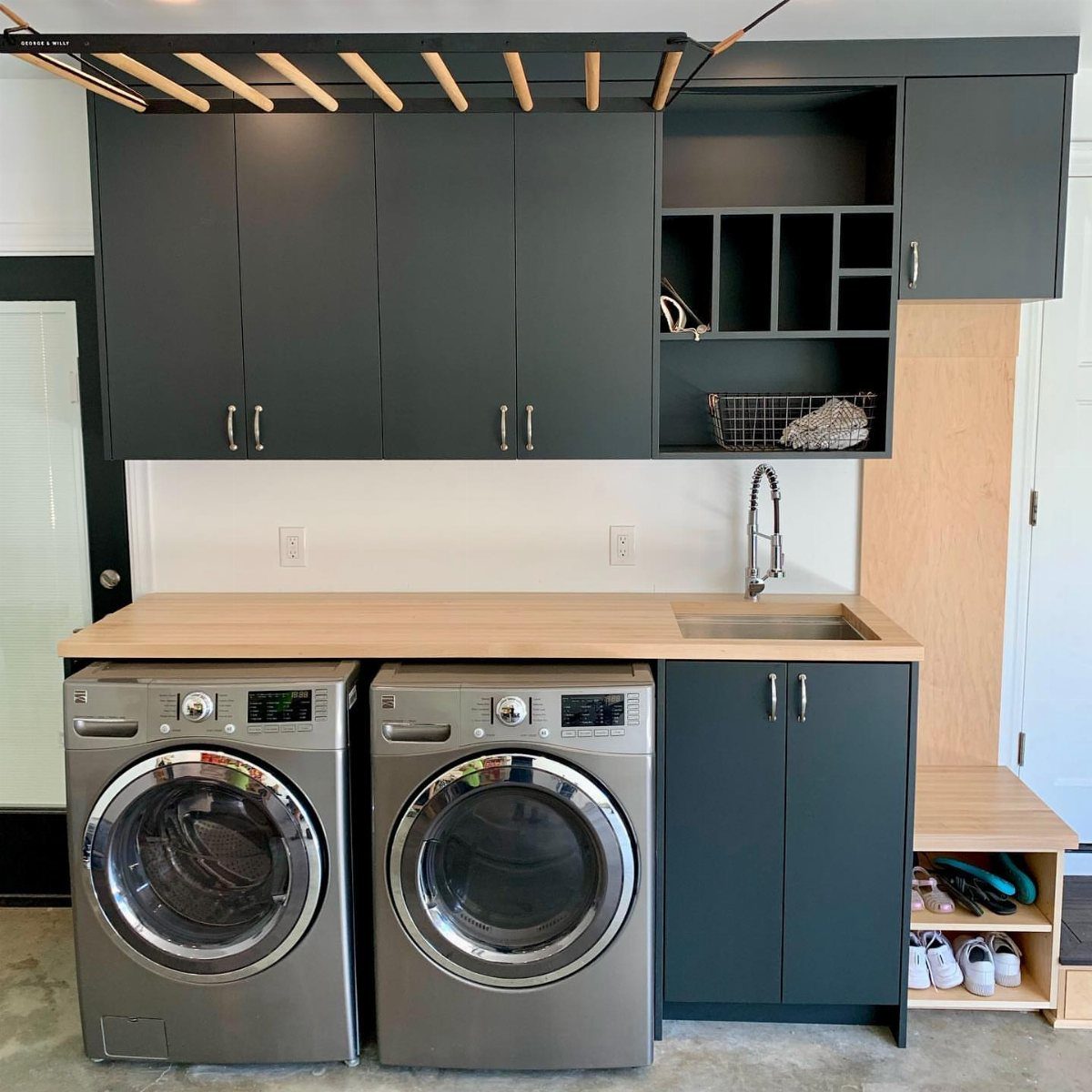 Built-in stainless steel sink in a garage mudroom with grey cabinets and laundry machines.