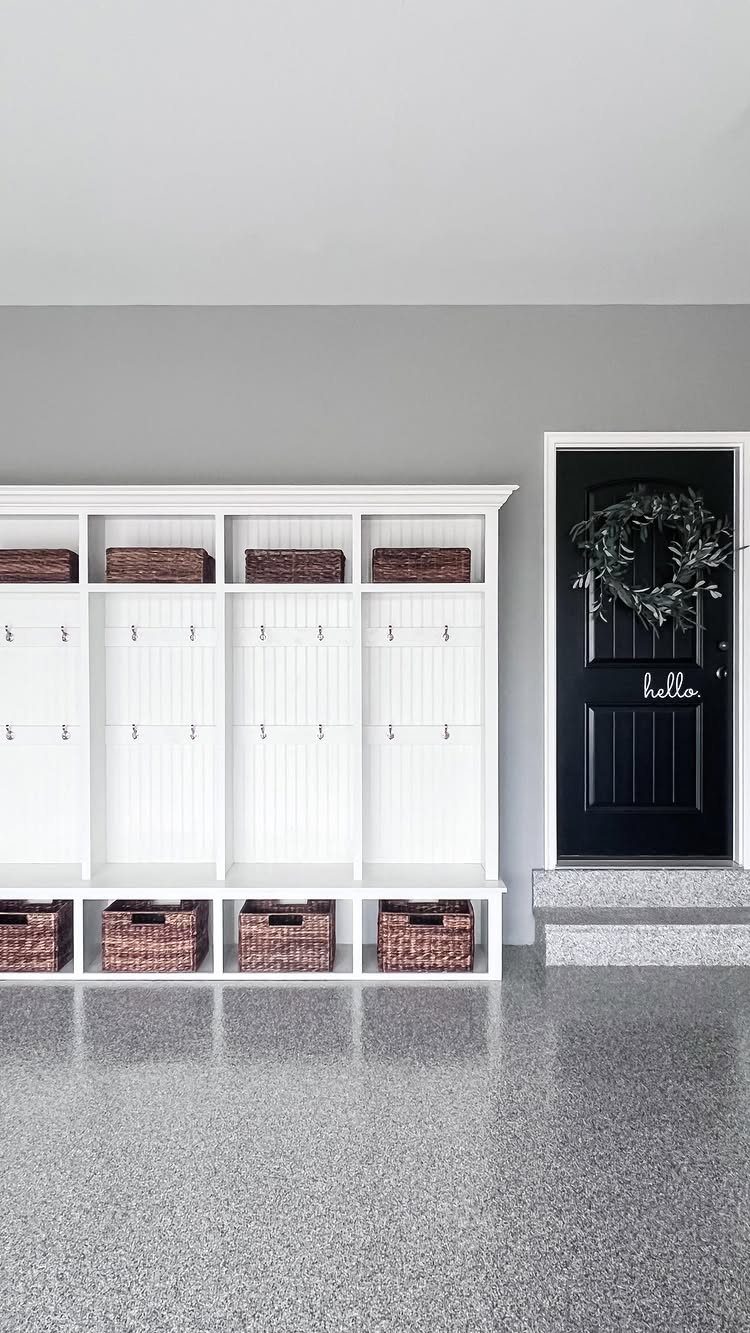 Grey epoxy flake flooring in a mudroom with white lockers and black door.