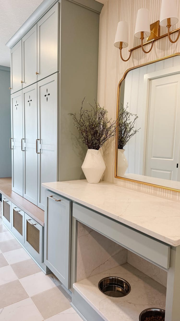 Light blue-grey mudroom with lockers, marble countertop, and built-in dog feeding station.