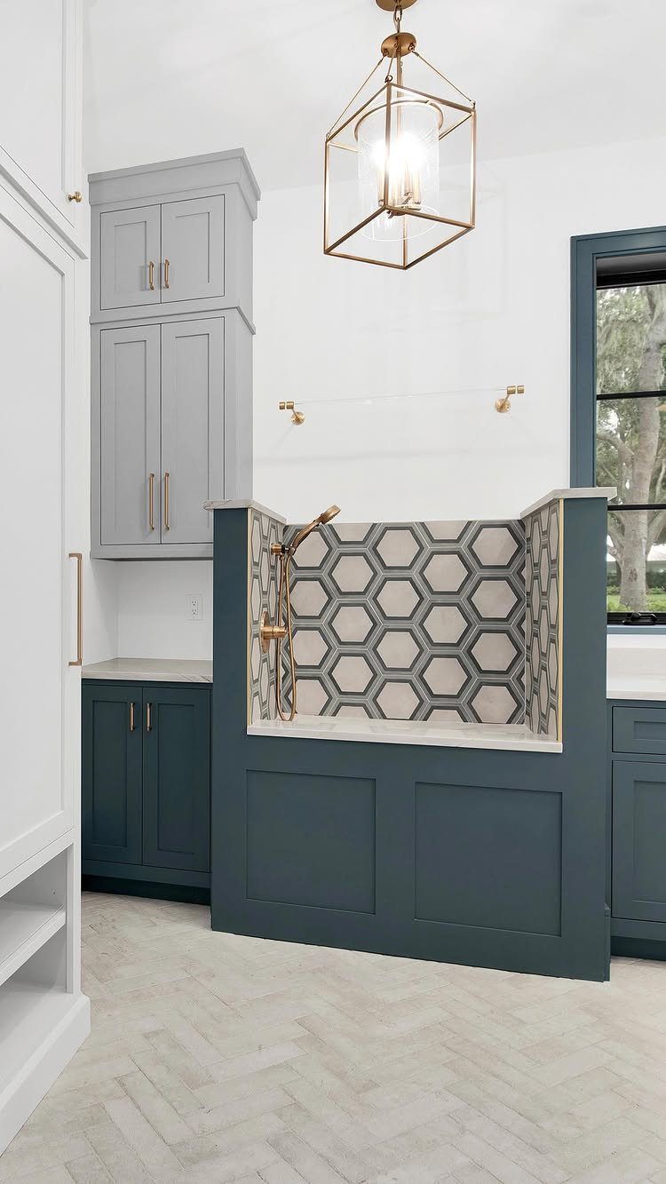 Dog wash station with hexagonal tiles and blue cabinetry in a modern mudroom.
