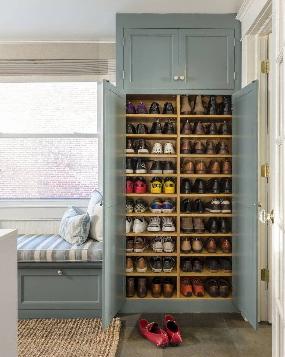 Blue-grey built-in cabinet with wooden cubbies filled with organized shoes and footwear.