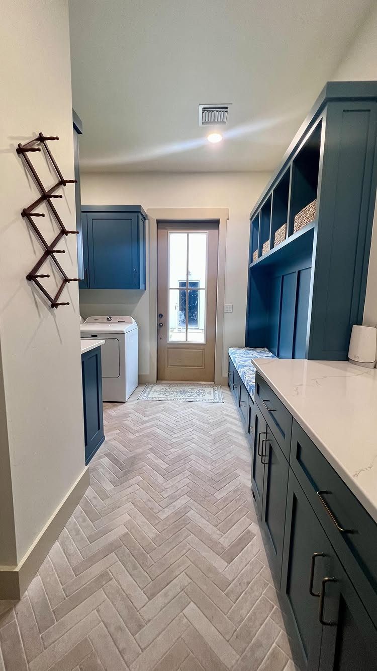 Blue built-in cabinetry with open shelving and a laundry machine in a mudroom.