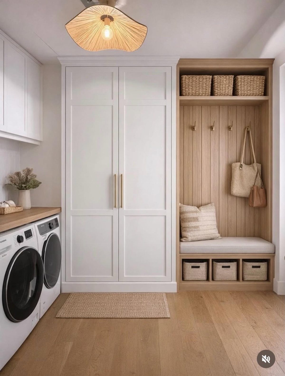 Laundry machines and a wooden mudroom bench with storage in a bright room.