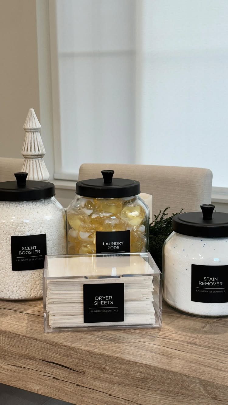 Laundry supplies in labeled glass jars and an acrylic box on wooden surface