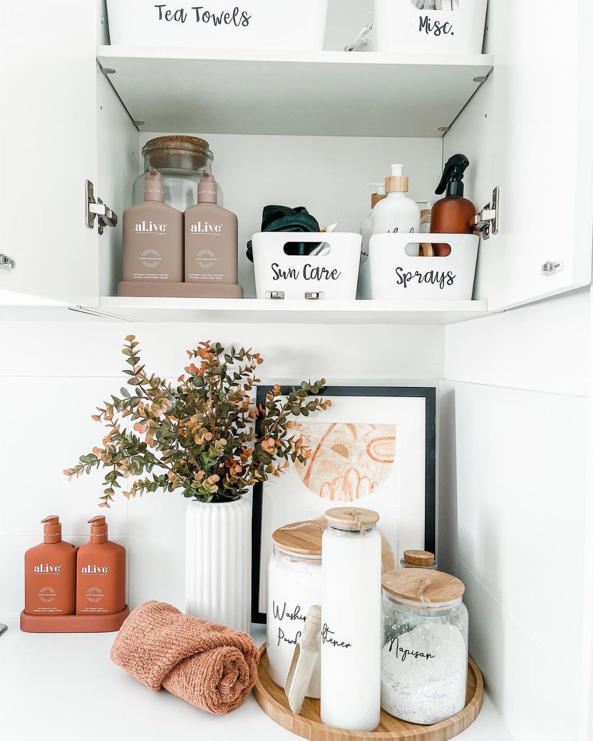 White laundry cabinets with labeled storage bins and organized supplies on a countertop.