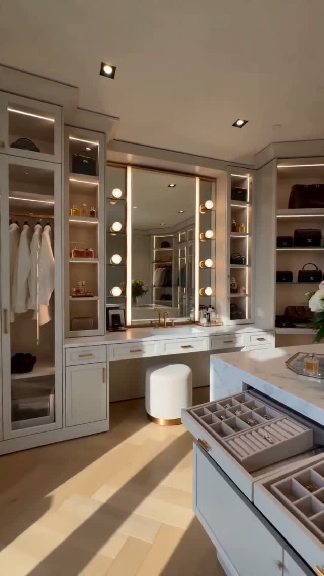 Luxurious white walk-in closet with vanity mirror and jewelry organizer island