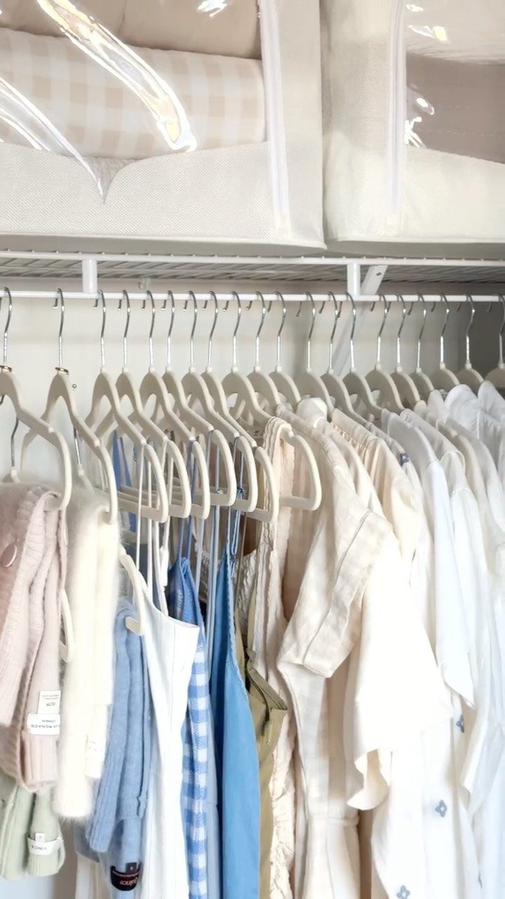 White matching hangers holding light-colored clothing in an organized walk-in closet.