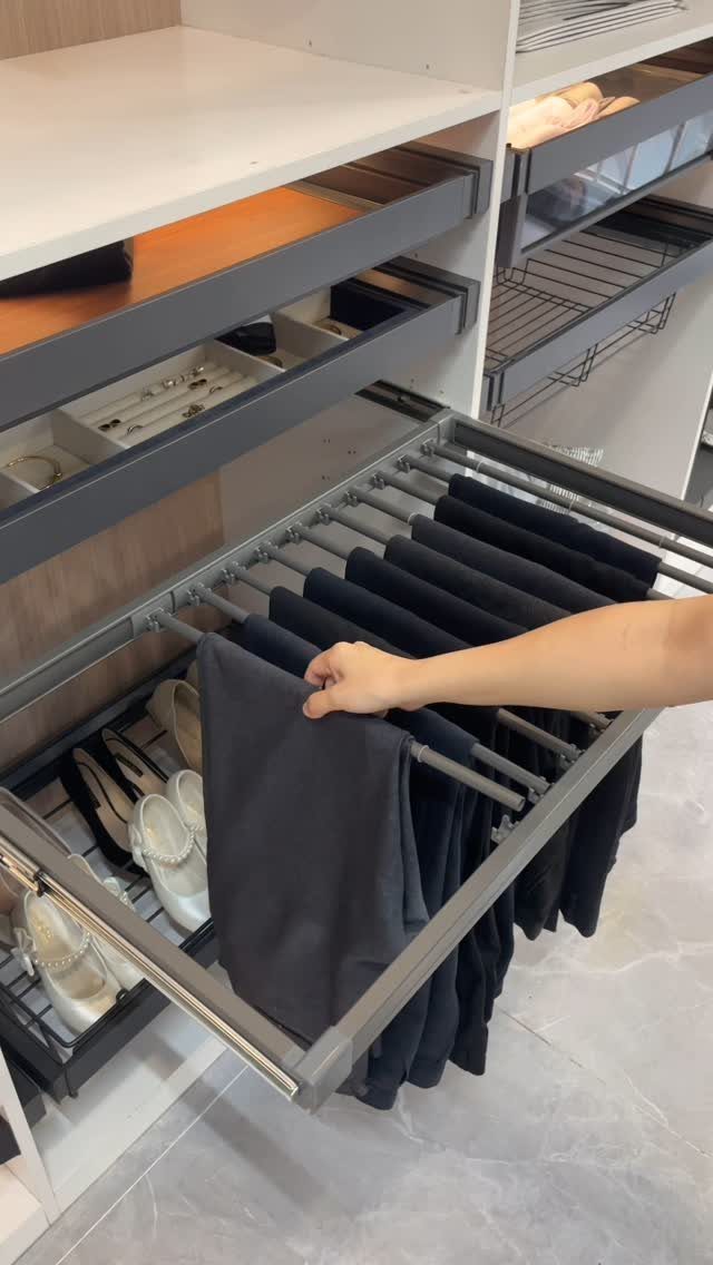 Pull-out sliding rack with dark trousers in a modern white walk-in closet