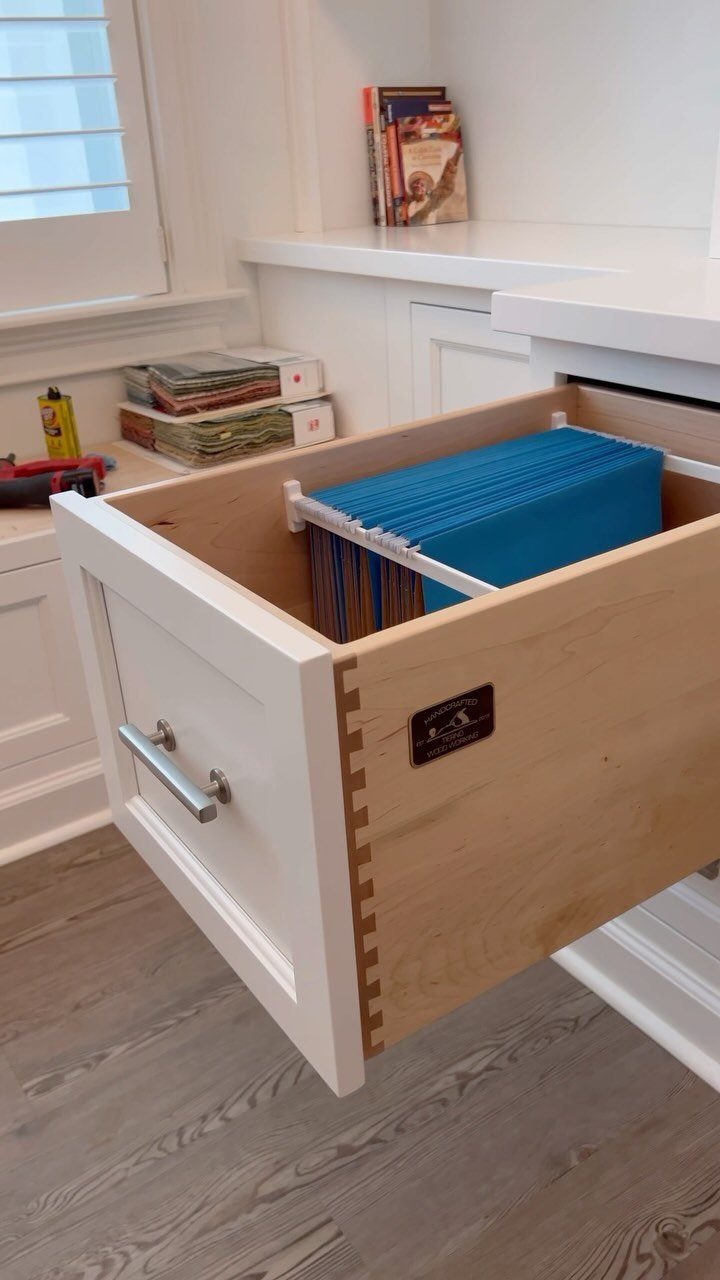 Open white desk drawer containing blue hanging file folders for organized document storage.