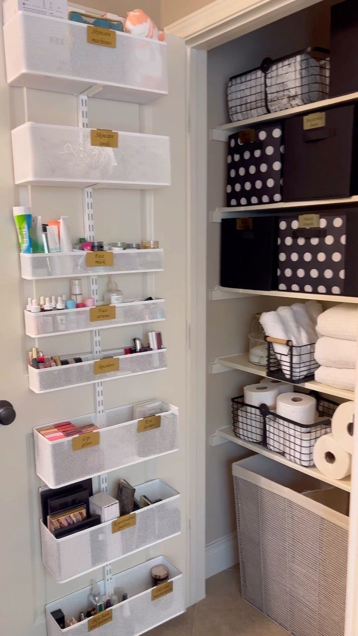 White mesh organizers on a door and shelves with bins in a bathroom.