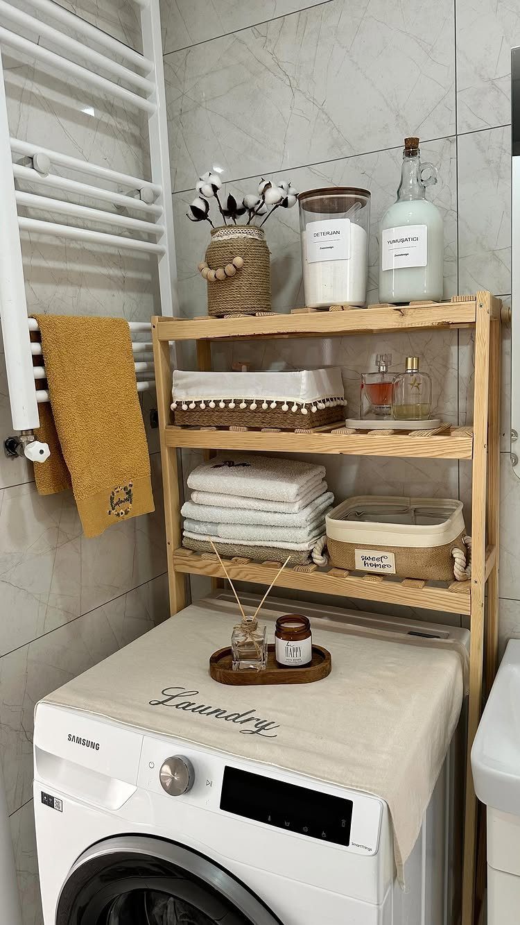 Wooden shelving unit with towels and jars over a white washing machine.