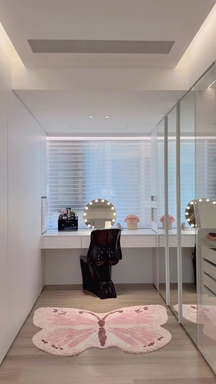 Modern white dressing room with a vanity, lighted mirror, and pink butterfly rug.