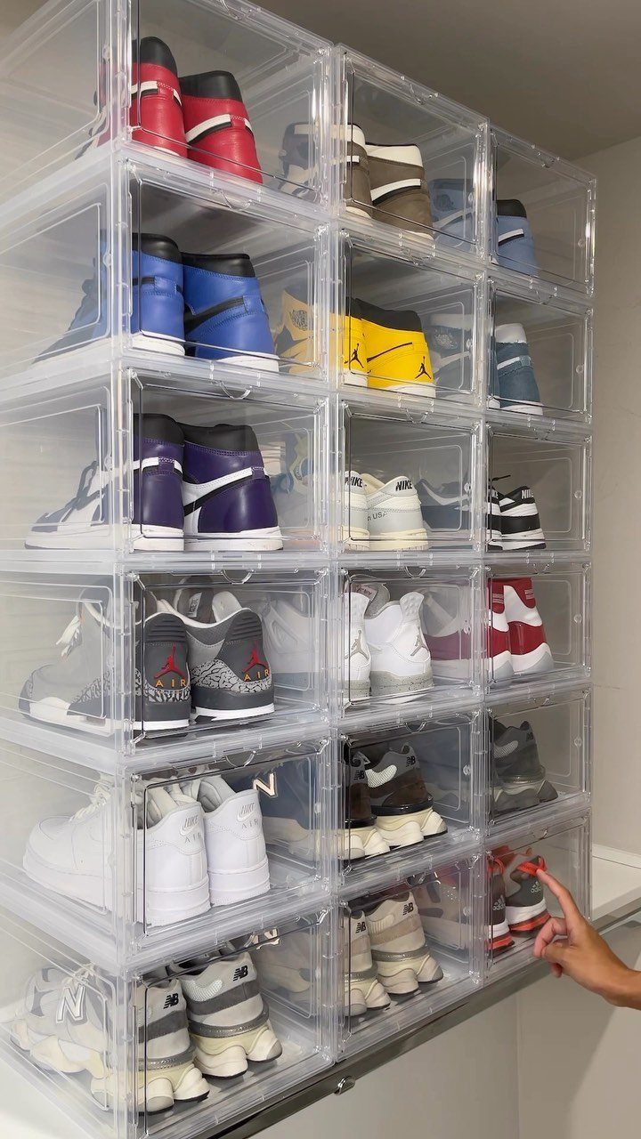 Clear plastic shoe boxes stacked vertically containing various colorful sneakers and athletic shoes.