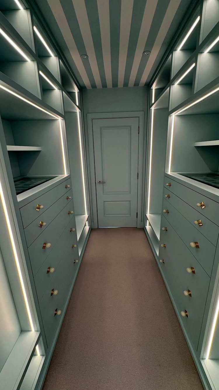 Light blue walk-in closet with built-in drawers, LED lighting, and striped ceiling.