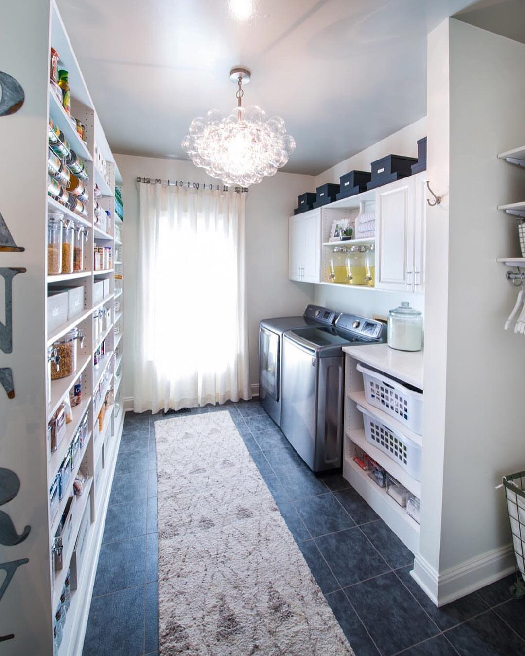 Pantry shelving and laundry machines in a combined utility room with white cabinetry.
