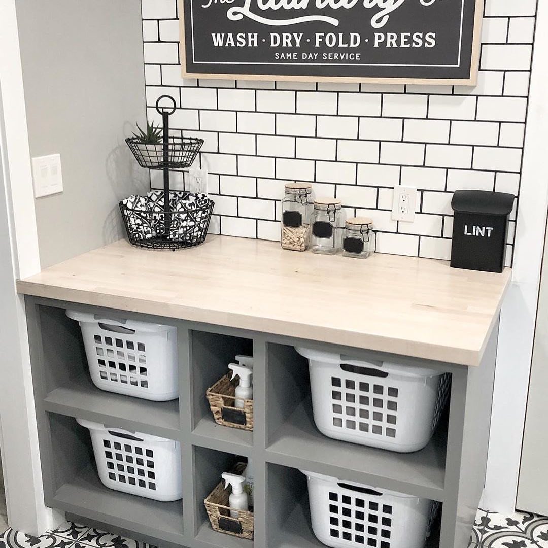 Light wood countertop folding station with grey shelving and white laundry baskets below.