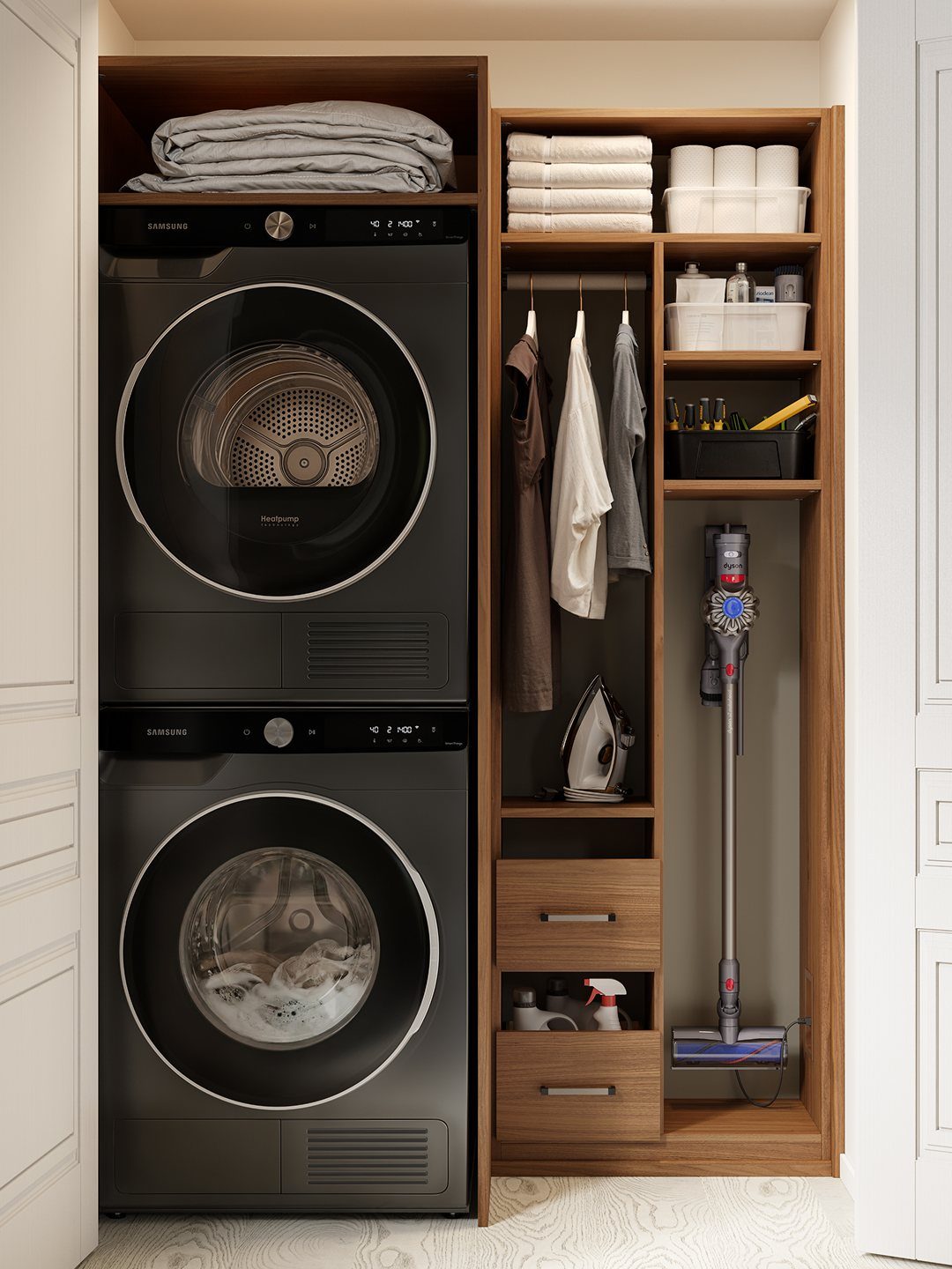 Stacked washer and dryer next to a wooden cabinet with hanging clothes and vacuum.