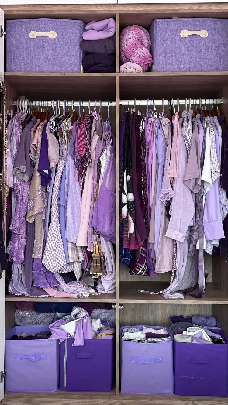 Purple and lavender clothing arranged by color in a wooden reach-in closet.