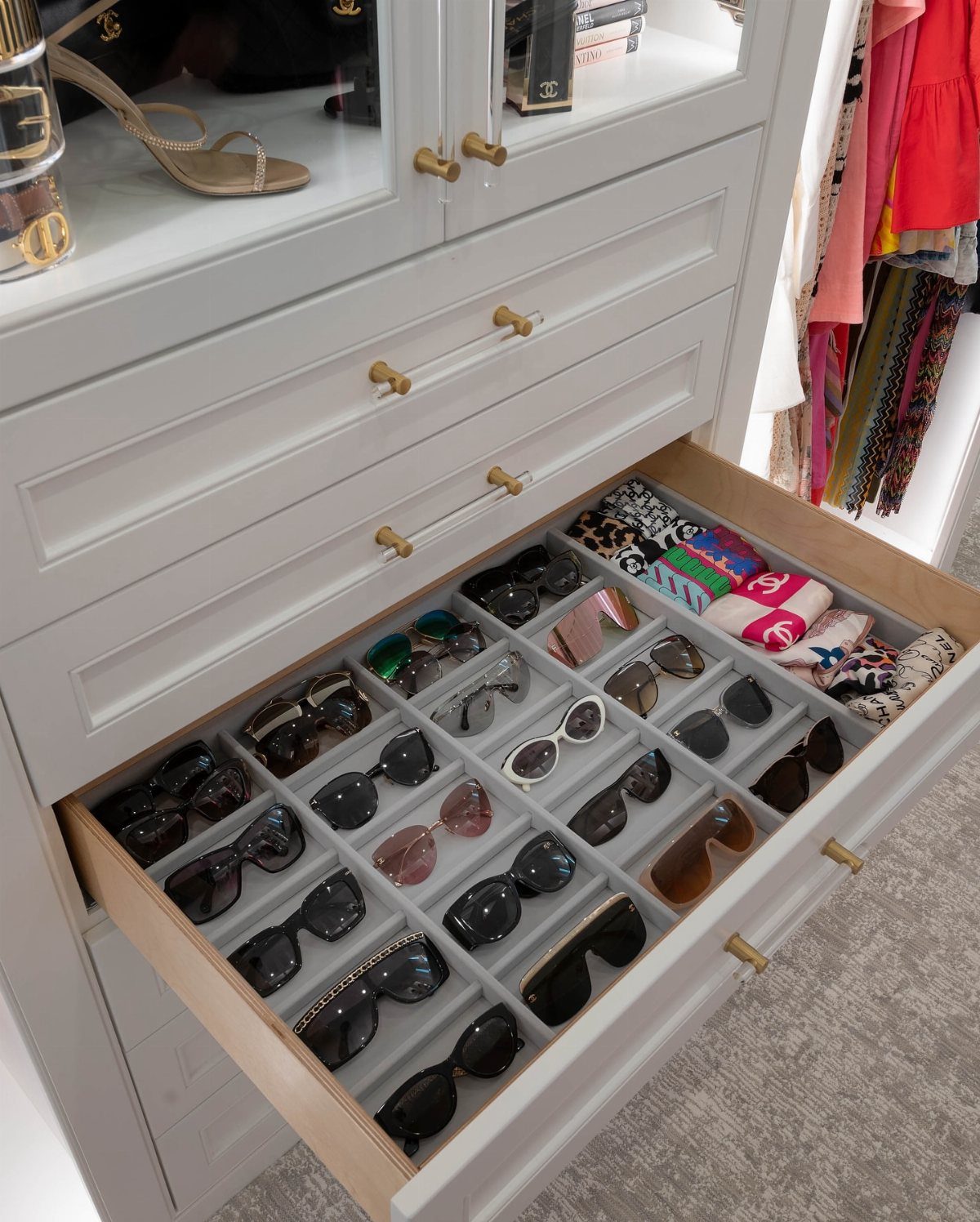Open white dresser drawer with clear acrylic dividers organizing sunglasses and accessories.