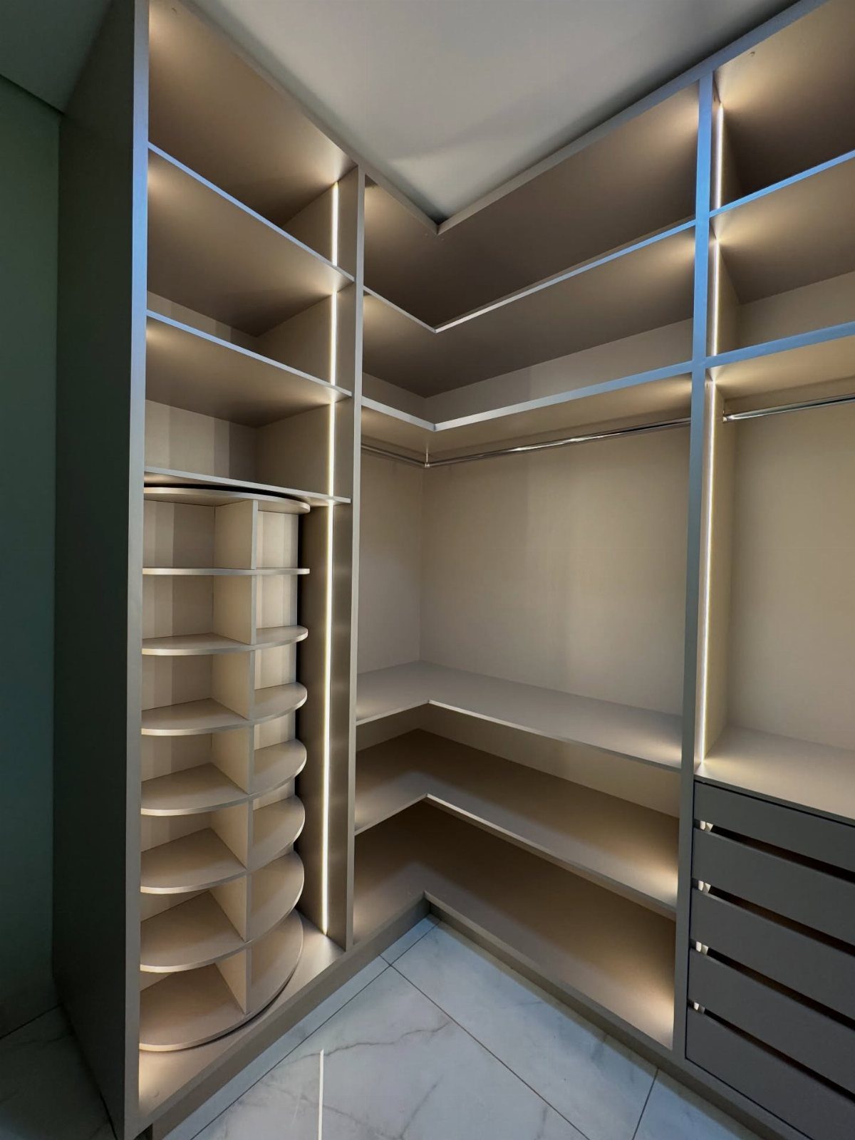 Modern reach-in closet with beige shelves, integrated lighting, and a pull-out shoe rack.