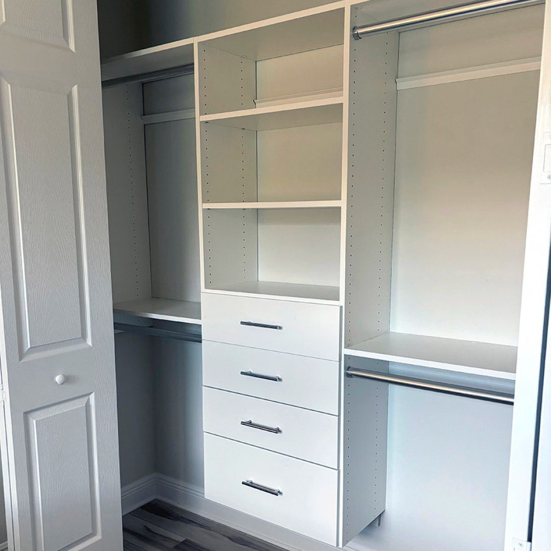 White reach-in closet system with built-in shelves, drawers, and hanging rods.