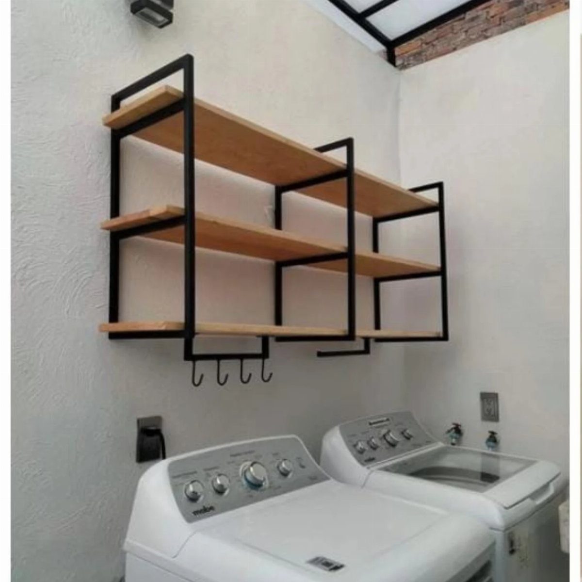 Black metal and wood shelves mounted on a wall above white laundry machines.