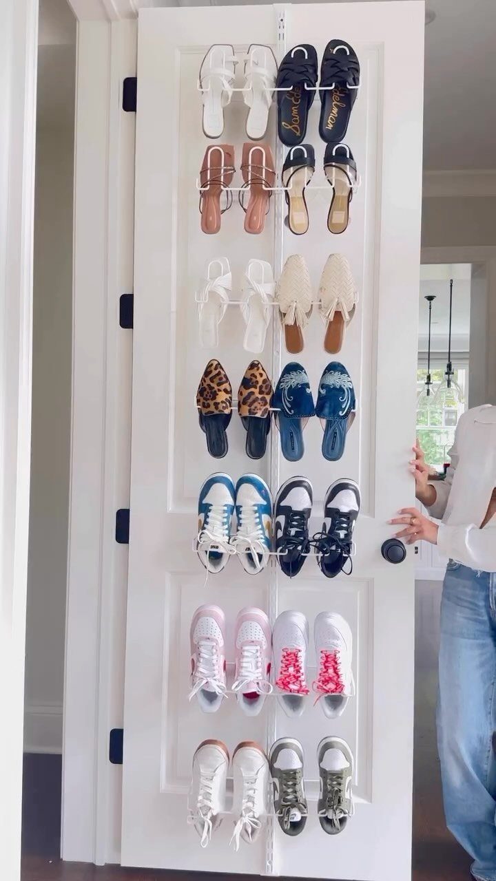 Clear plastic over-the-door shoe rack filled with various shoes on a white door.