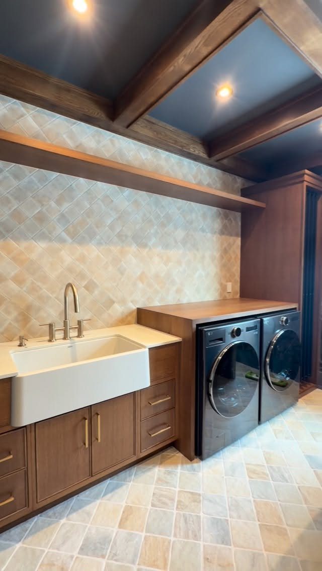 Side by side washer and dryer under a wooden counter in a laundry room