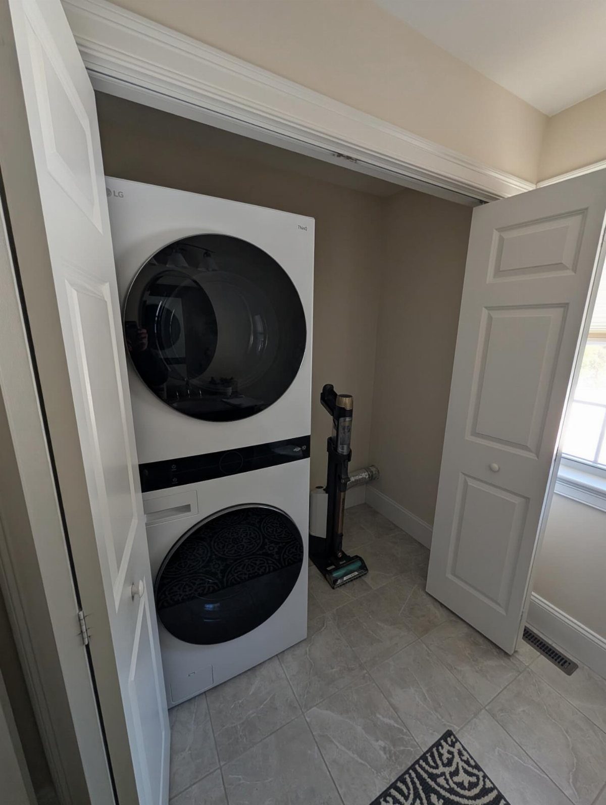 Stacked white washer and dryer units inside a laundry closet with open doors.