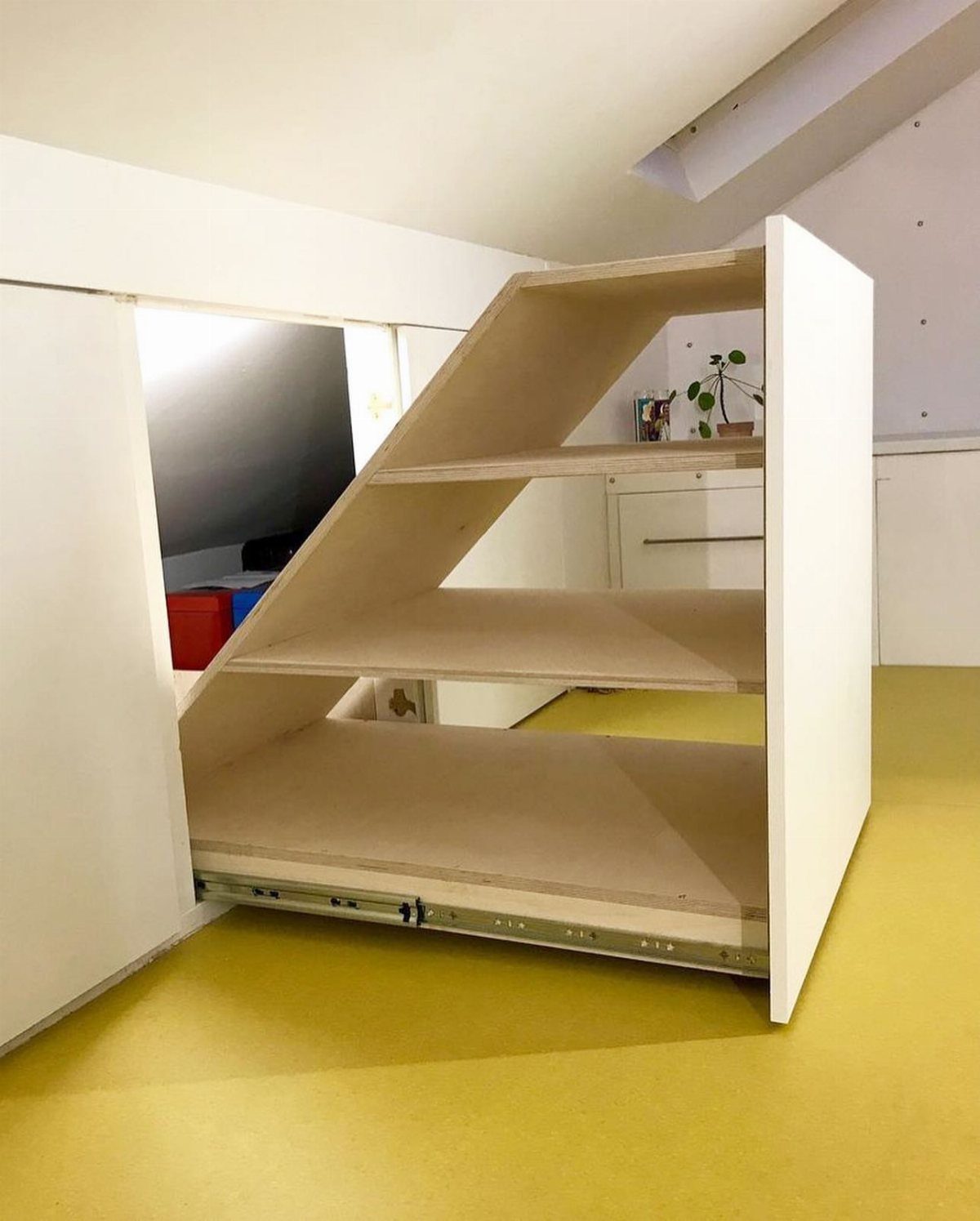 Pull-out white closet shelf with a slanted top for under-roof storage.
