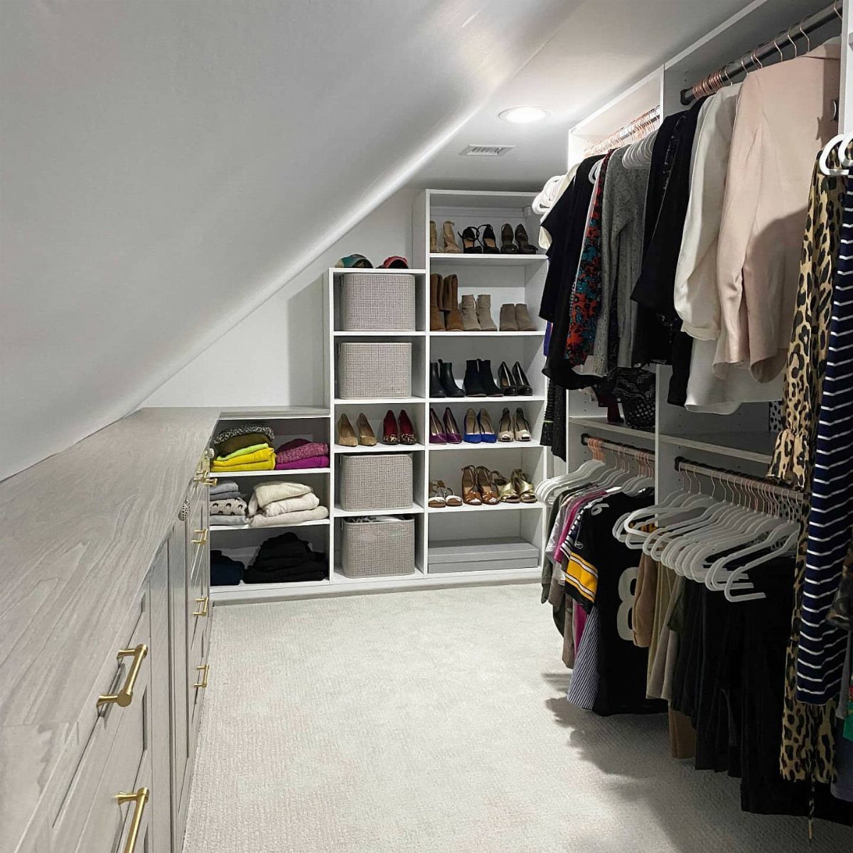 Walk-in closet with double hanging rods and shelving under a sloped white ceiling.