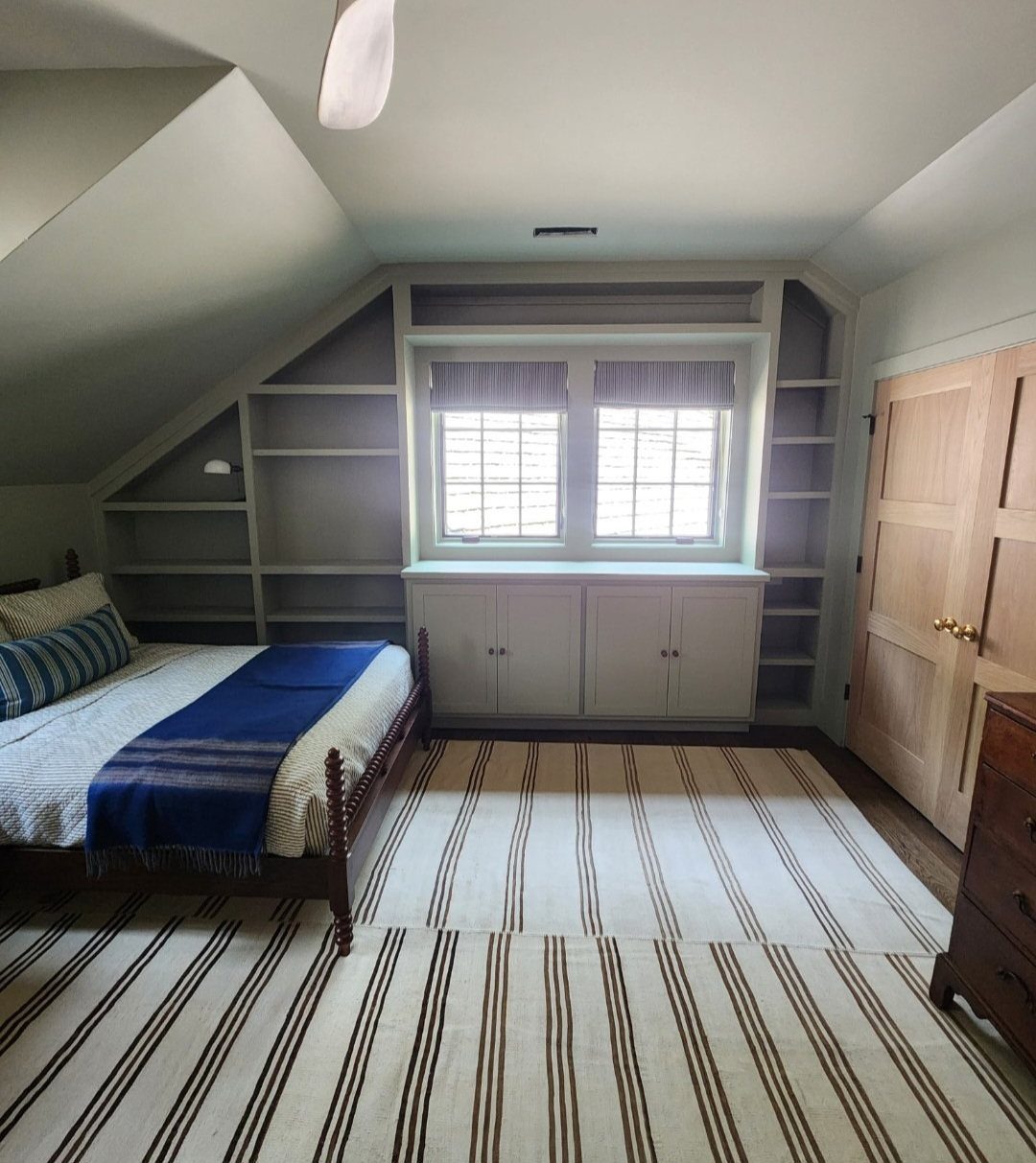 Built-in grey shelves following the slope of a ceiling in a bedroom.