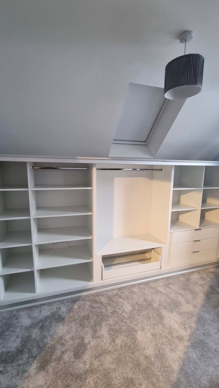 White built-in closet system with open shelving under a sloped attic ceiling.