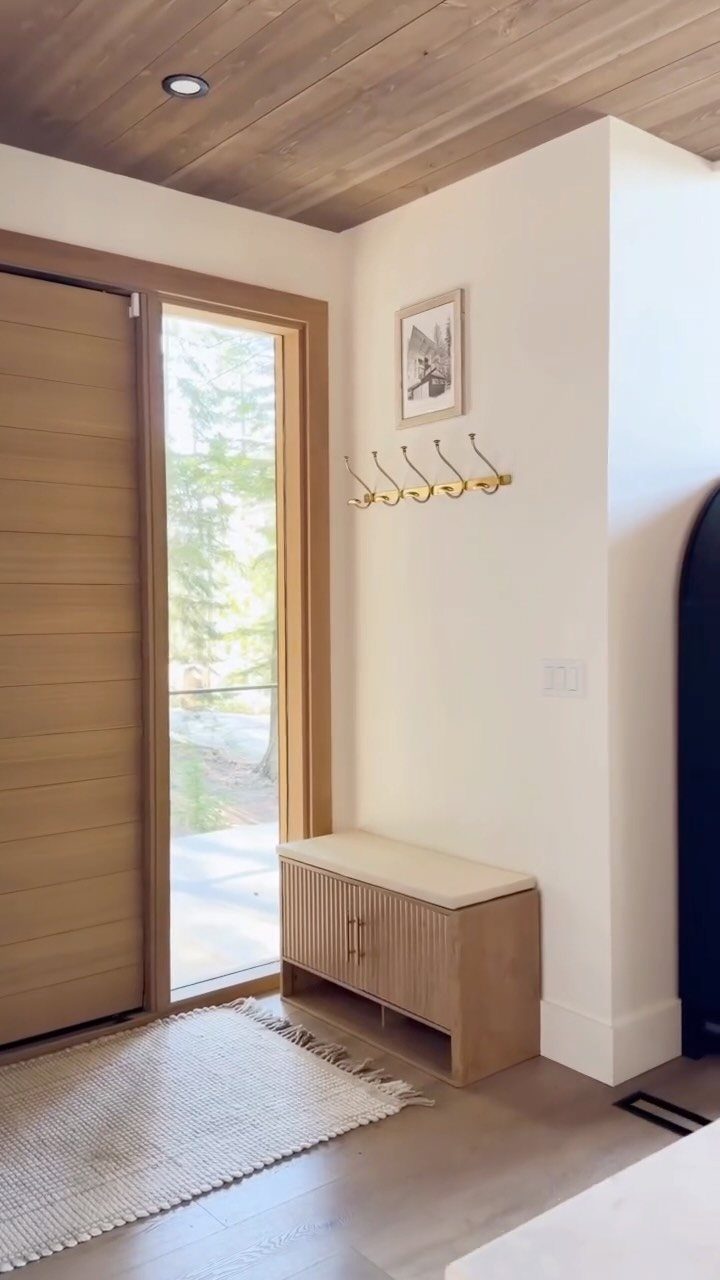 Light wood storage bench with cream cushion in a bright modern entryway