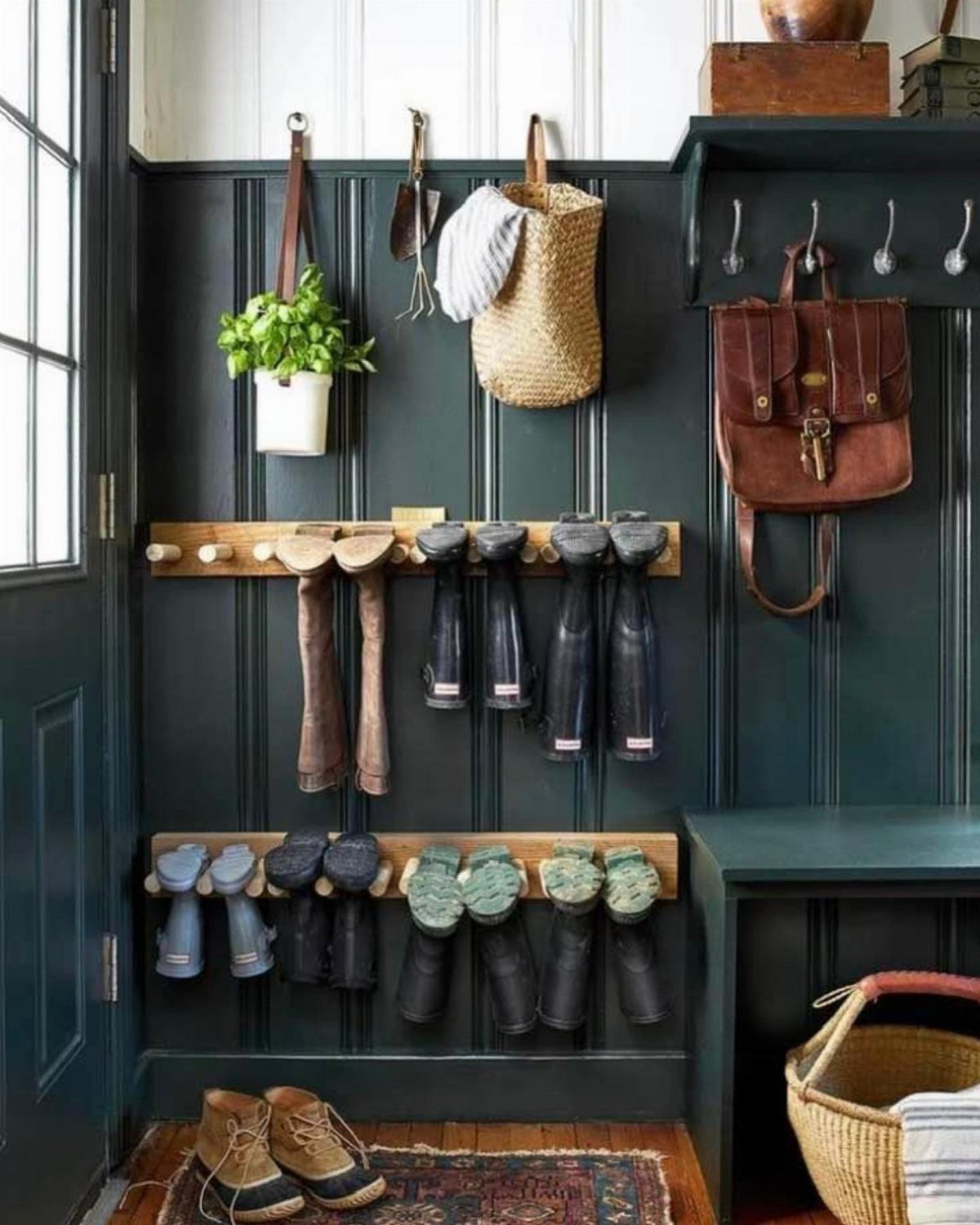 Boots hanging on wooden peg racks against a dark green paneled entryway wall.