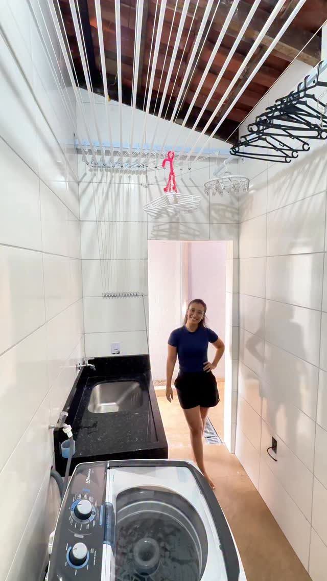 Ceiling-mounted drying rack in a narrow laundry room with a woman and washing machine.