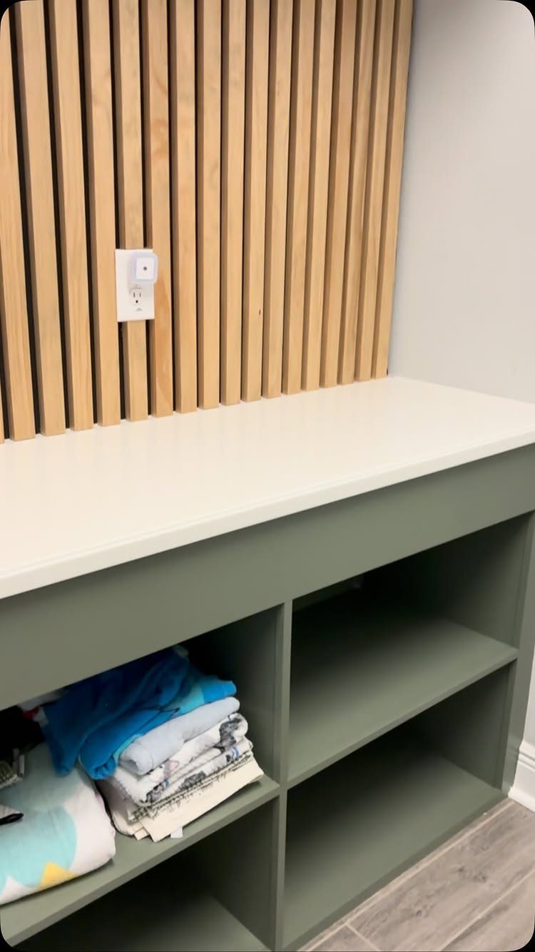 White countertop with sage green open shelving and vertical wood slat wall backdrop.