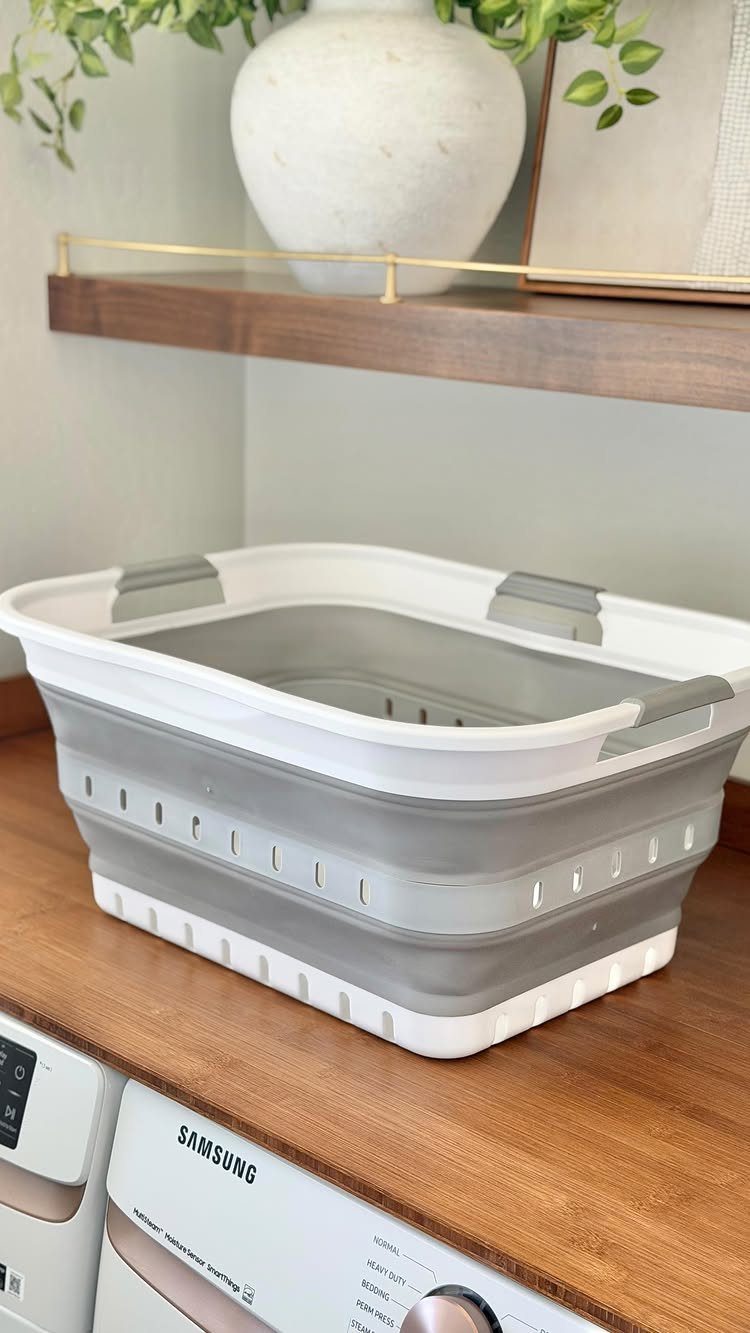 Collapsible laundry basket on a wooden counter above a white Samsung washing machine.