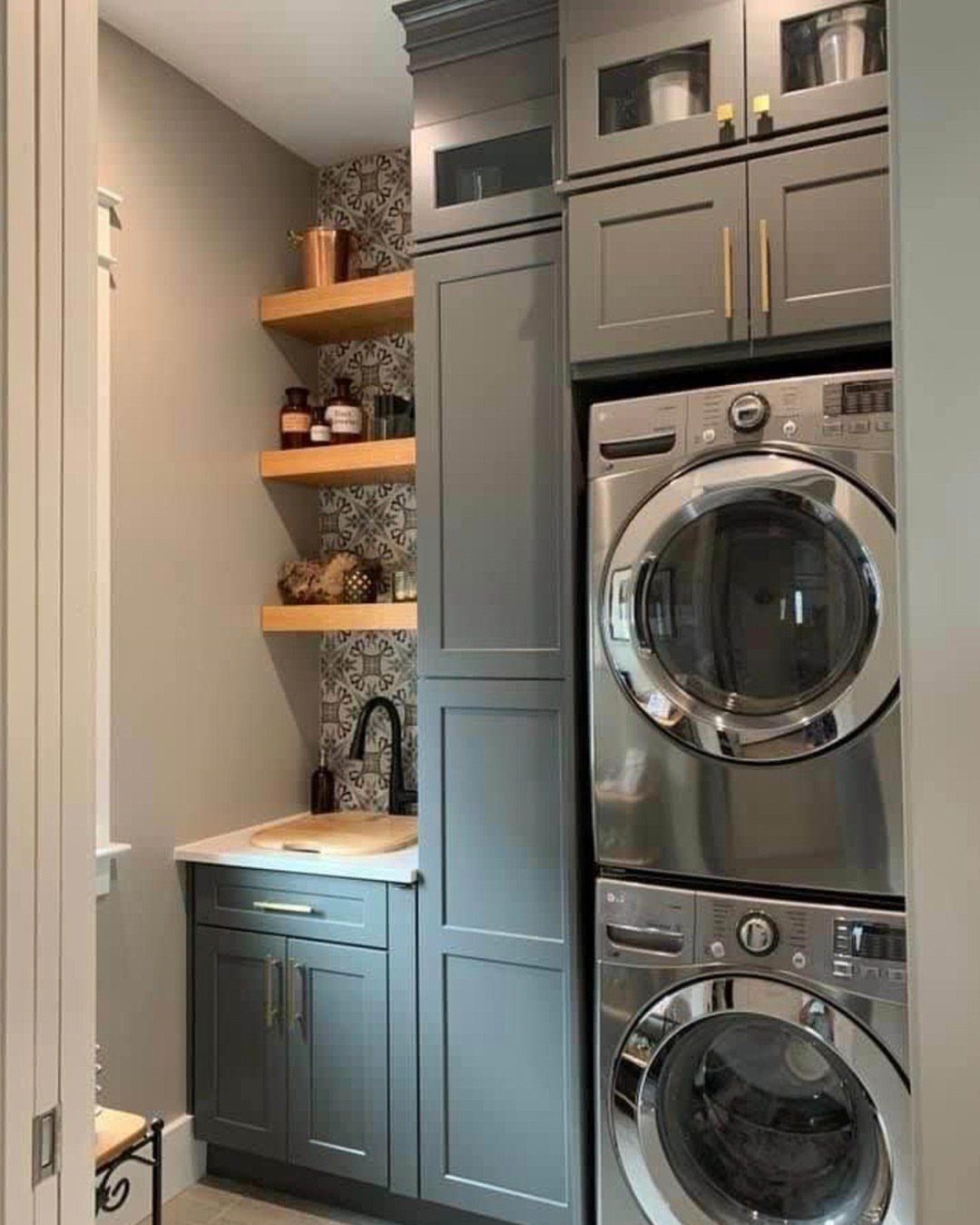 Grey floor-to-ceiling cabinets surrounding a stackable washer and dryer in a small laundry room.