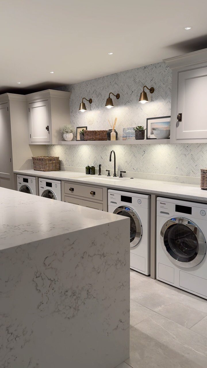 White marble laundry island in a modern room with white appliances and cabinets.