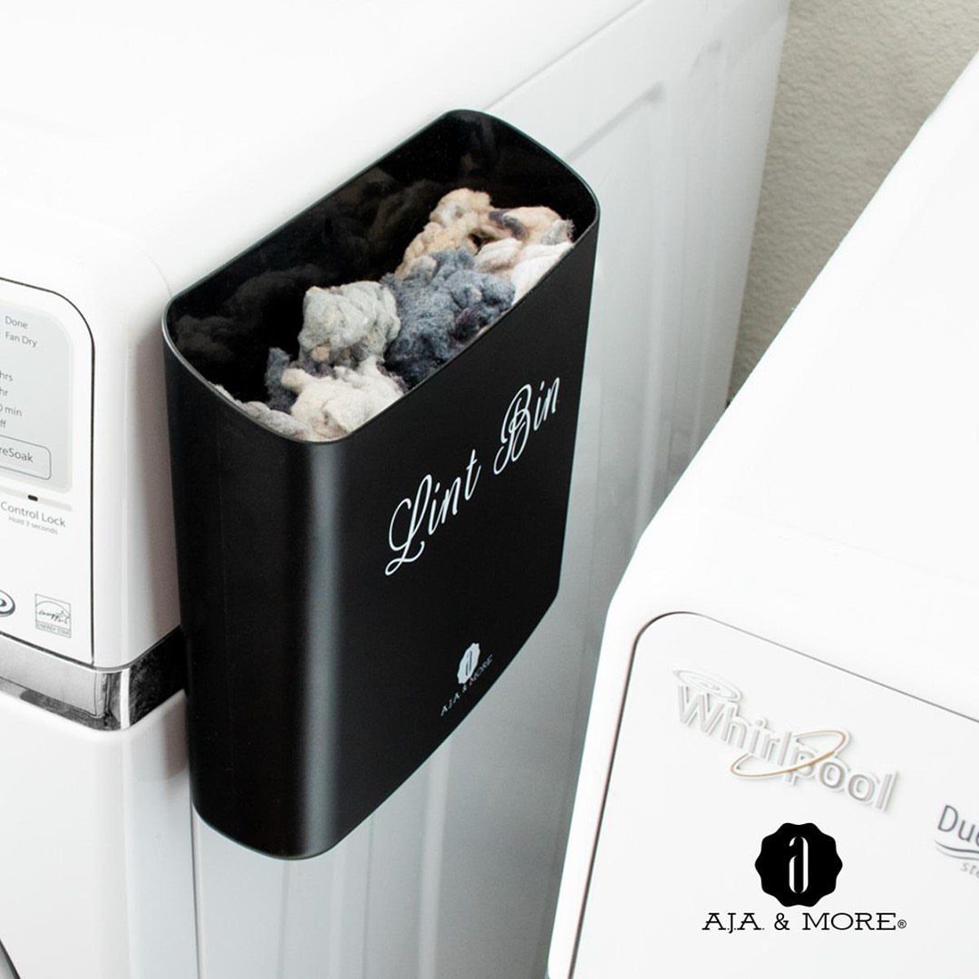 Black magnetic lint bin attached to a white washing machine filled with lint.