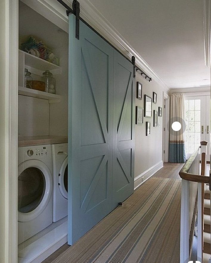 Light blue sliding barn door partially opening to reveal a small laundry area.