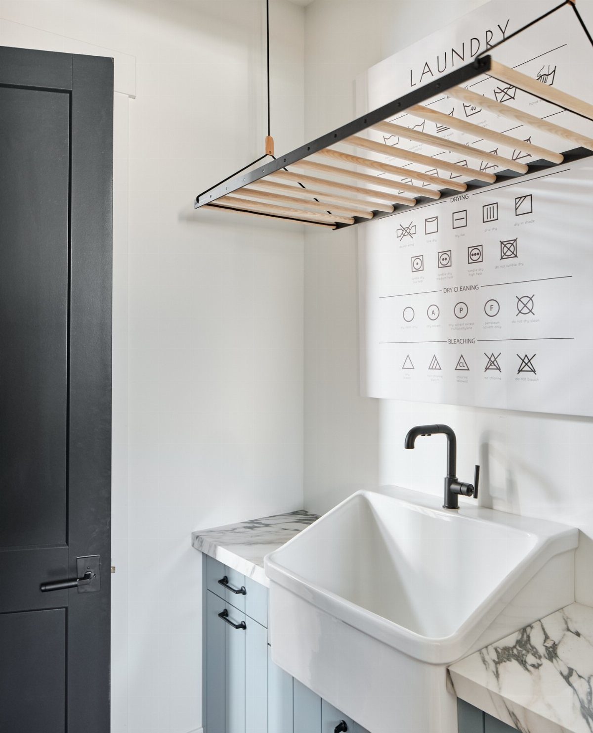 Wooden slatted drying rack hanging above a white utility sink in a laundry room