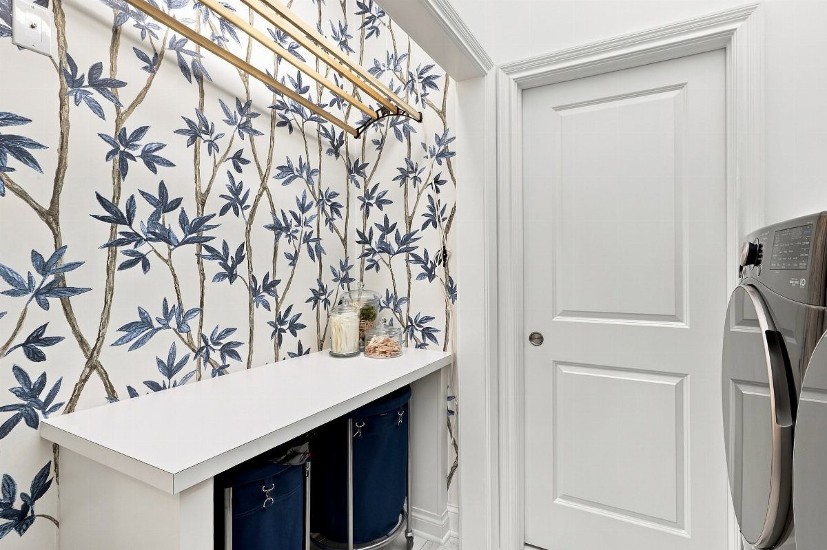 Blue and white botanical wallpaper in a small laundry room with white counters.