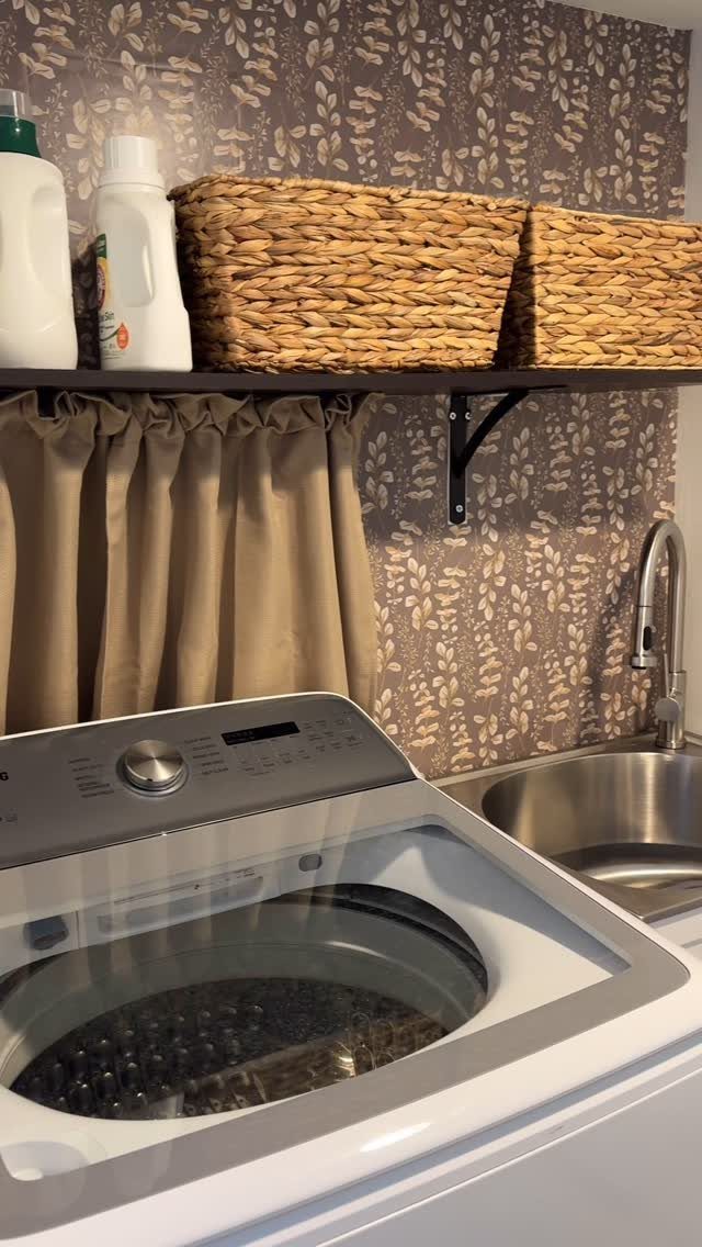 Botanical pattern wallpaper in a small laundry room with washing machine and baskets.