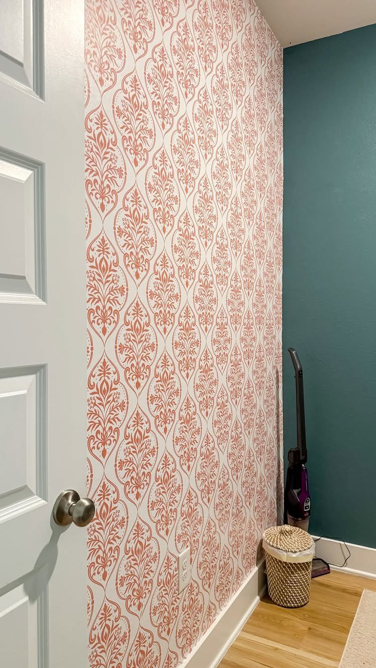 Orange and white damask wallpaper in a small room with teal walls.