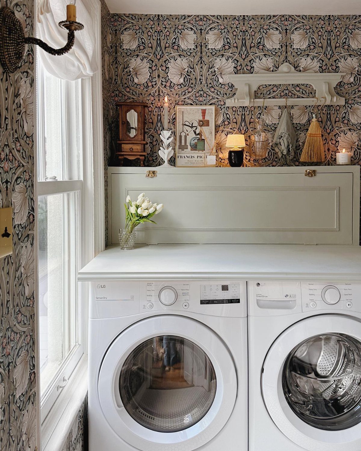 Vintage floral wallpaper in a small laundry room with white washing machines.