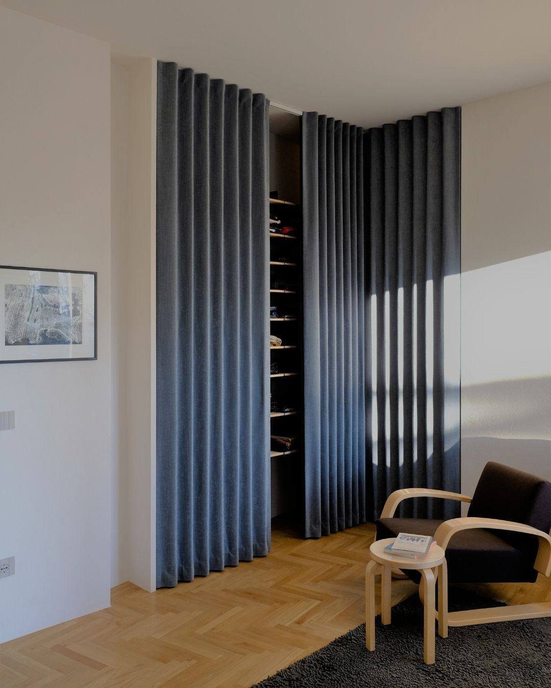Dark grey pleated curtains used as closet doors in a modern minimalist room.