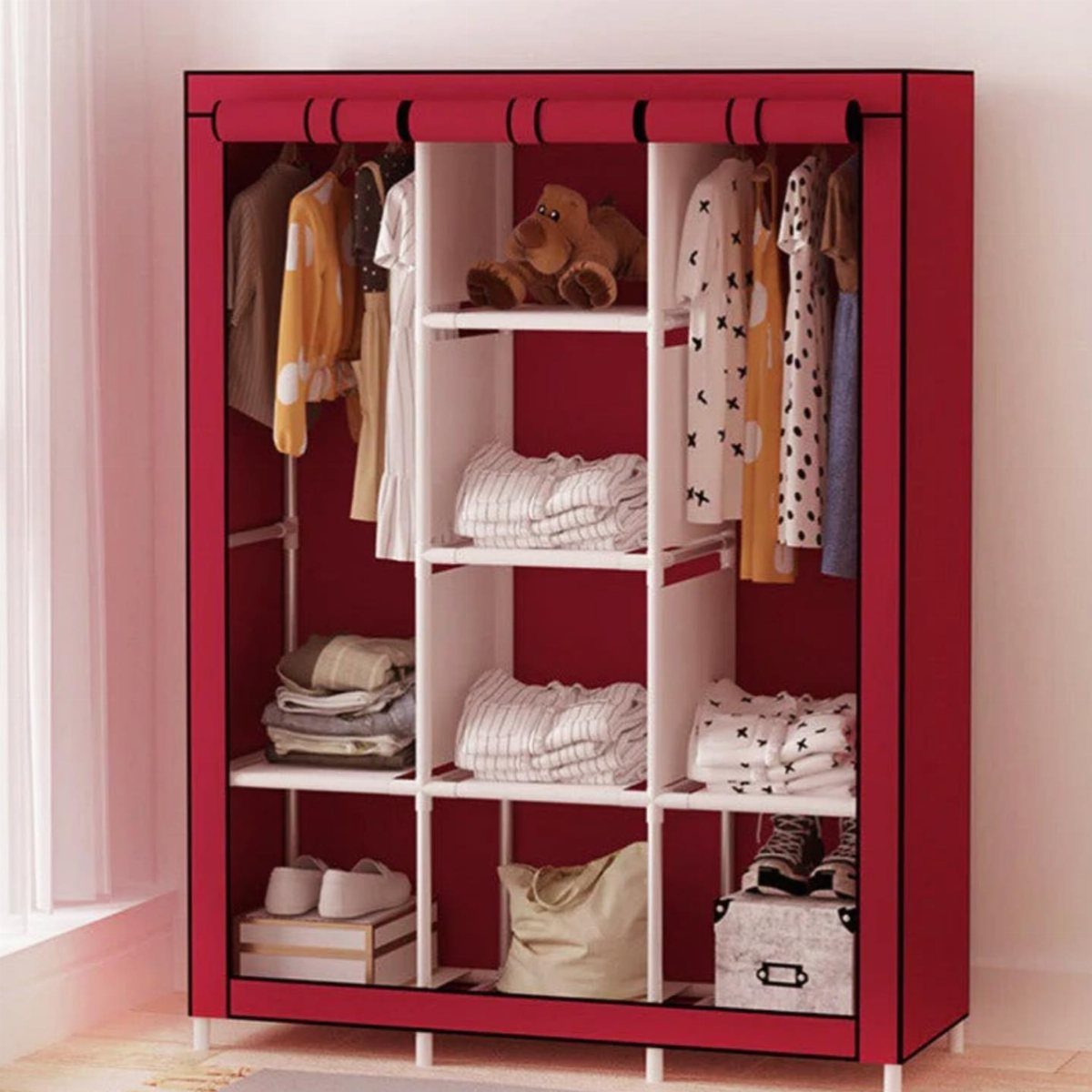 Red portable fabric wardrobe with white shelves and hanging clothes in a room.